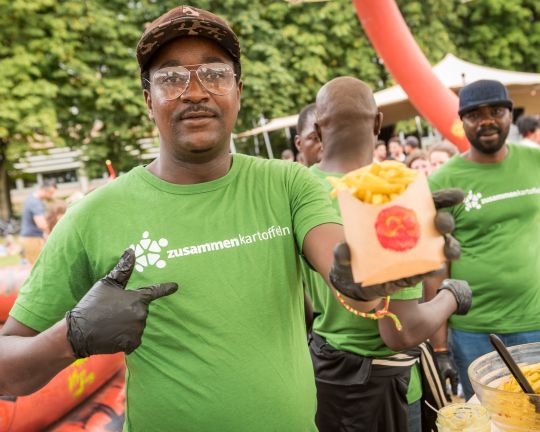 Eine Person bereitet Pommes zu auf dem Agrikulturfest.