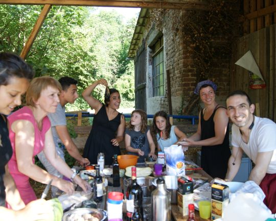 Viele Personen stehen um einen großen Tisch und bereiten Essen zu.