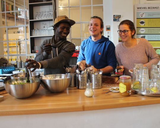 Drei Personen stehen hinter der Theke und lachen.