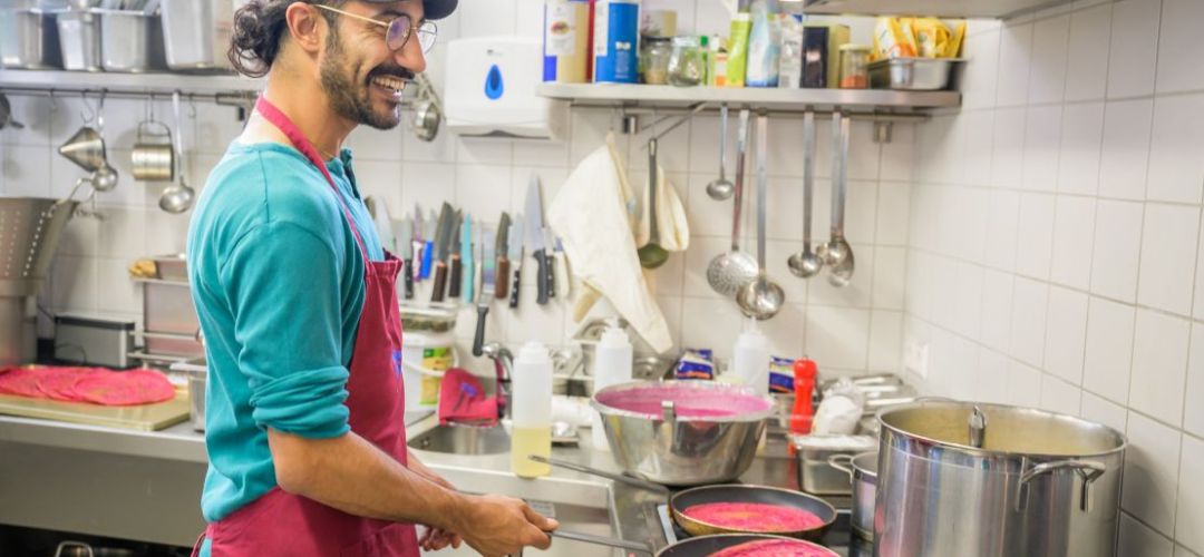 Der Koch steht am Herd und bereitet Essen zu.