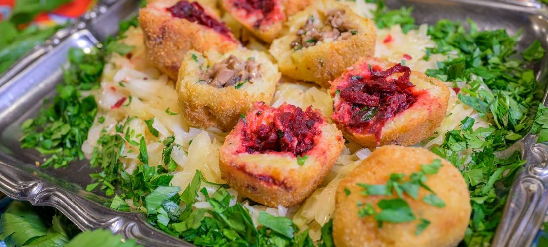 Vegetarische brasilianische Coxinhas halbiert angerichtet auf einer Platte mit Petersilie und Zwiebeln.