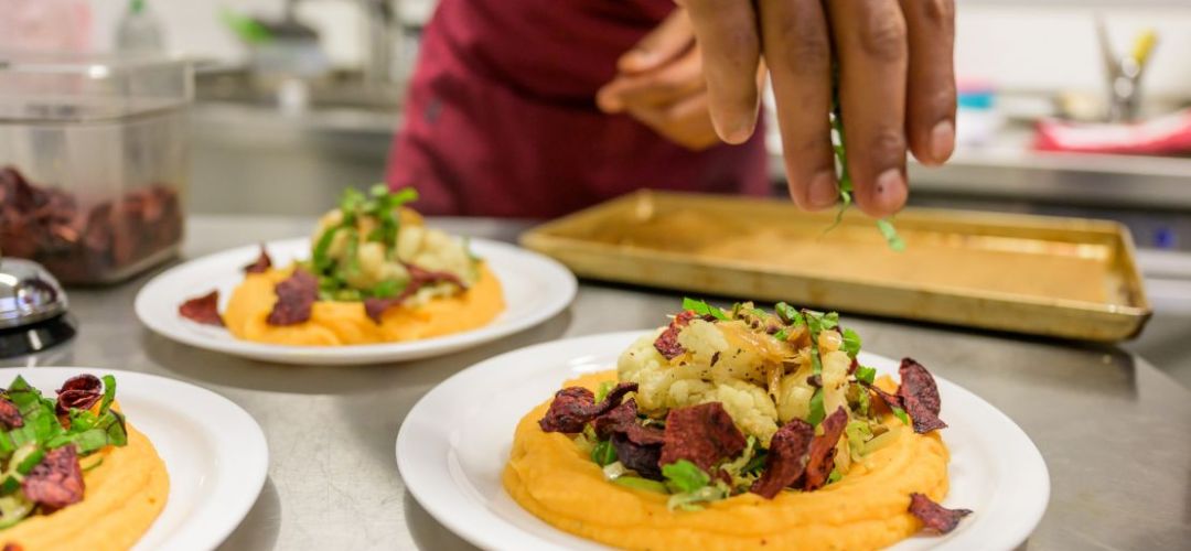 Der Koch dekoriert einen Teller mit Essen.
