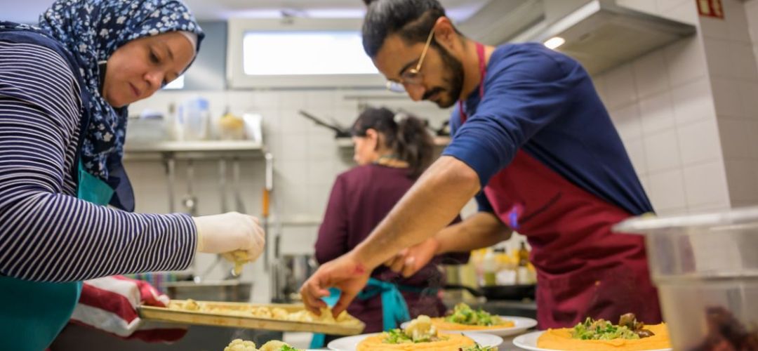 Die Küchenmitarbeiter bereiten das Mittagessen zu.