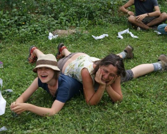 Zwei Personen liegen im Garten aufeinander und lachen.