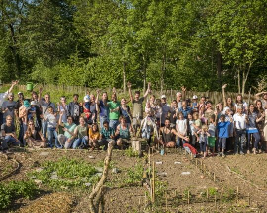 Eine große Menschengruppe steht im Gemeinschaftsgarten.