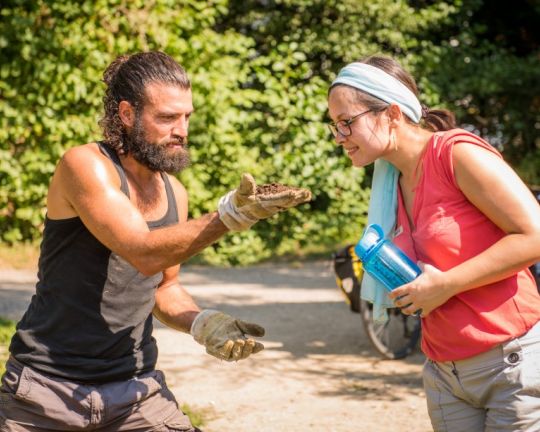 Zwei Personen sind im Garten und schauen sich Erde an.