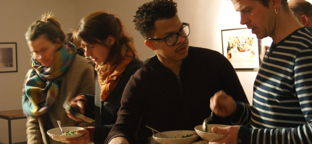 Vier Personen bedienen sich am Buffet und unterhalten sich miteinander.