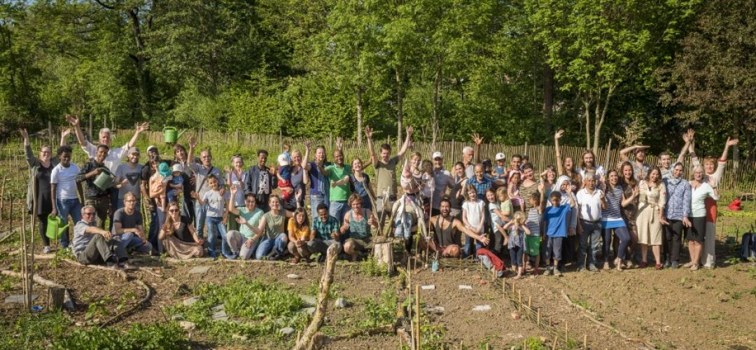 Eine große Menschengruppe posiert für ein Foto im Gemeinschaftsgarten.