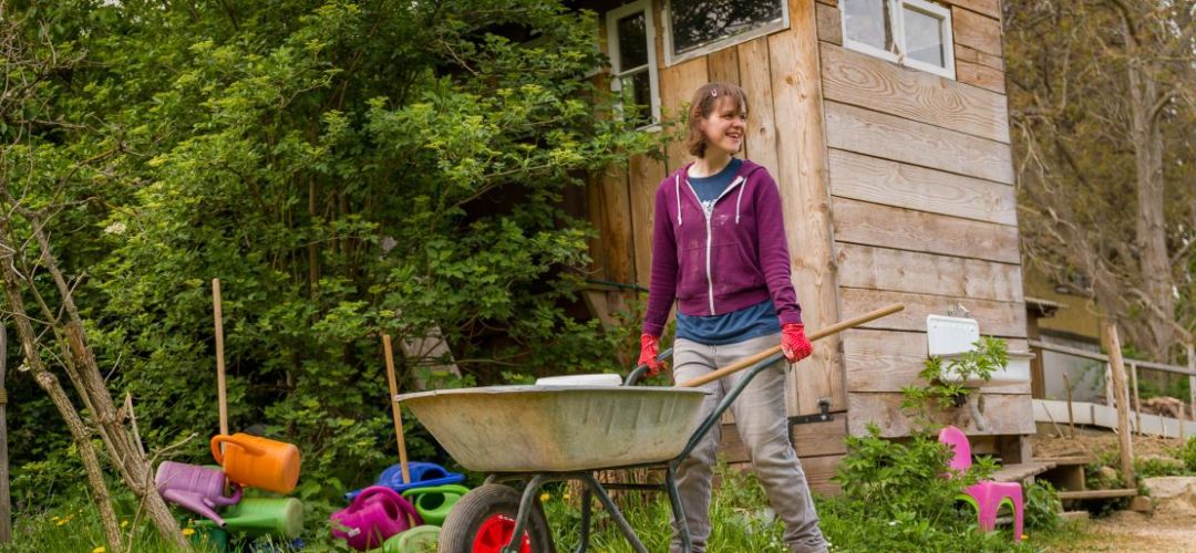 Eine Person schiebt eine Schubkarre durch den Gemeinschaftsgarten.
