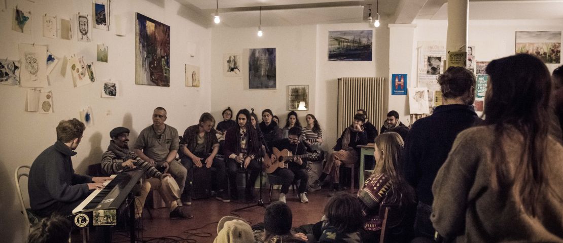 Das Red Moon Collective spielt im Strandcafe bei "zusammen on stage" ein Konzert.  Der Raum ist voll, Menschen sitzen aufdem Boden.