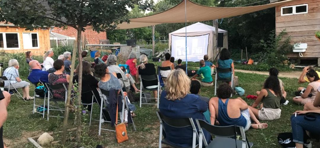 Freiluft Cine Arab im Gemeinschaftsgarten mit Leinwand und Publikum.