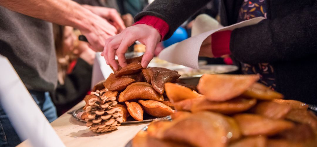 Volle Teller mit Empanadas und Hände die danach greifen.