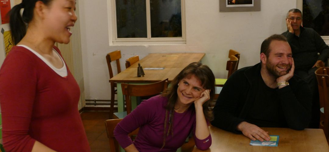 Eine Person erzählt etwas und zwei weitere hören zu und freuen sich.