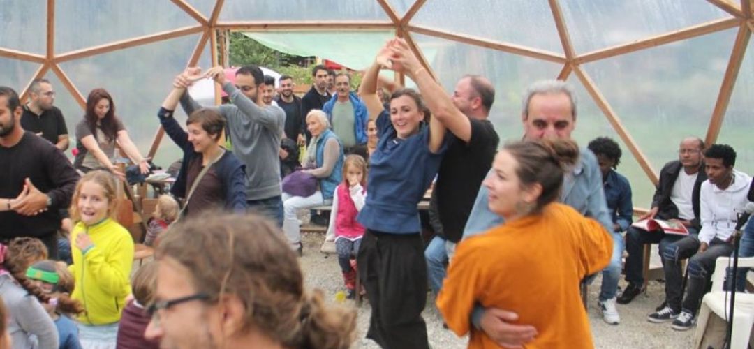 viele Menschen tanzen unter der Kuppel im Gemeinschaftsgarten.